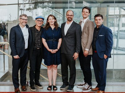 The six 2022-23 Fellows standing in front of a glass wall at the 2023 symposium
