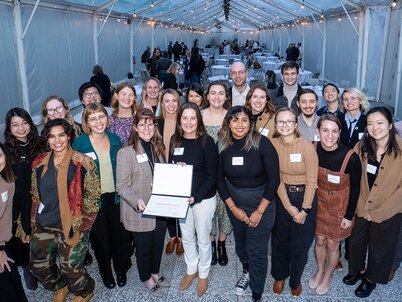 A group of Olmsted Scholars smiles while one holds a certificate