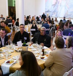 People seated at round tables conversing over dinner