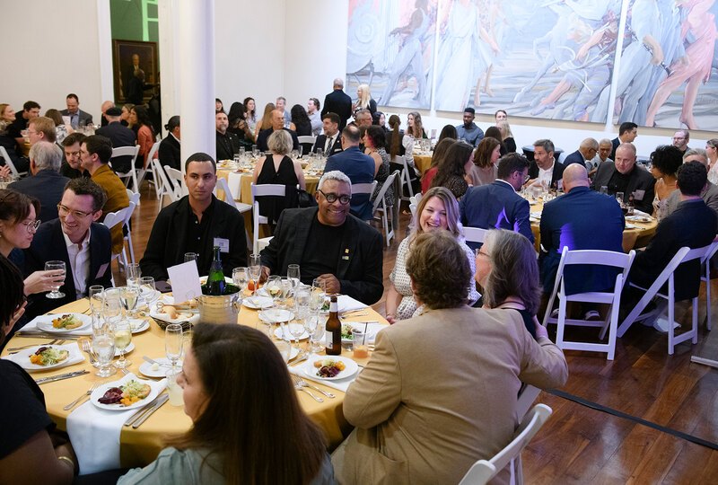 People seated at round tables conversing over dinner