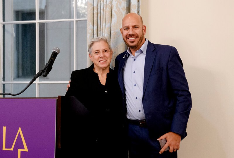 Kristina Hill and Michael Grove smile from next to a podium