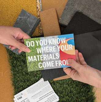 Two hands holding a postcard that says "Do you know where your materials come from?"