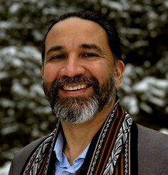 Headshot of Aiman Duckworth standing in front of snowy pine trees